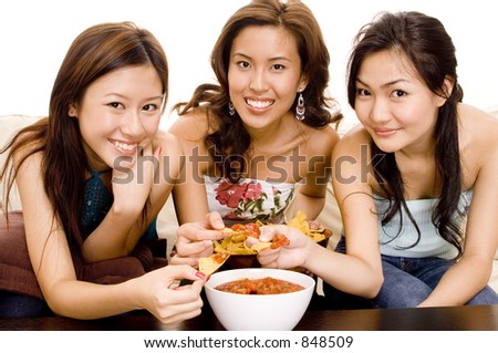Three pretty asian women eating nachos and salsa dip