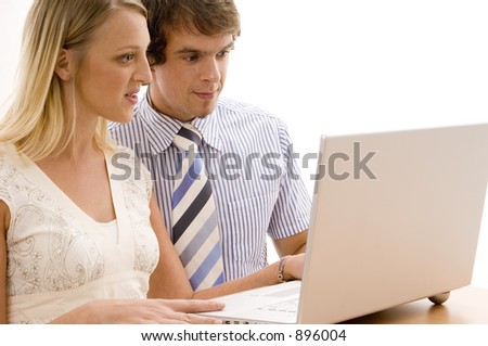 Two young business people using a silver laptop computer