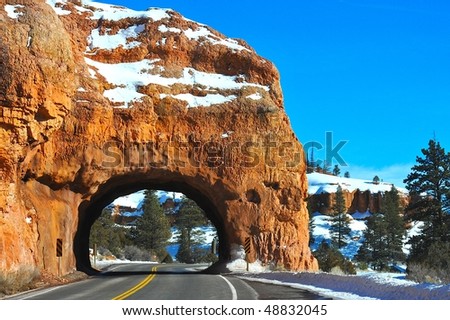 Road going through red rock tunnel in Utah USA