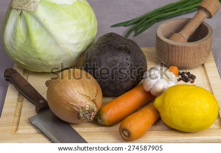 Onions, carrots, beets, cabbage, garlic and lemon on a chopping Board
