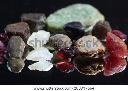Uncut and raw gem crystals. These natural rough gems  are from Lemmenjoki national park in Finnish Lapland.  Front row left to right: sapphire, moonstone, garnet, corundum, ruby.