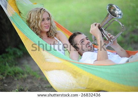 Young woman and man playing trumpet in hammock