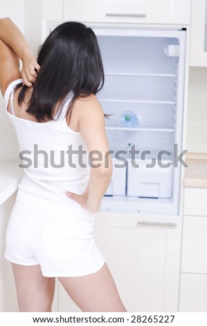woman standing in front of refrigerator looking in