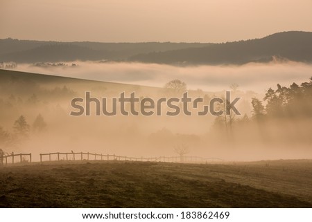 Foggy hills and valleys with fence in autumn dawn