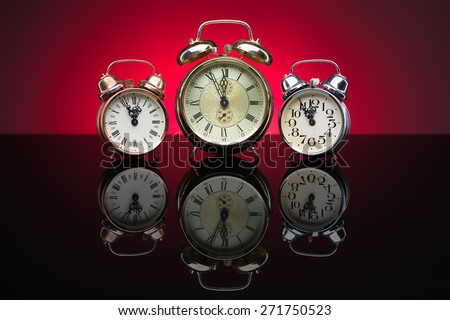 Vintage alarm clocks showing five minutes to twelve, red background