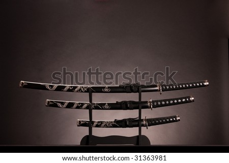 Three ancient japanese swords with a monochrome lighting. Text can be inserted in the upper part of the image.