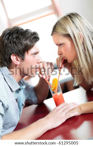 Beautiful woman and man in restaurant drinking from the same glass. Very shallow depth of field.