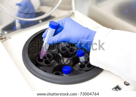 Scientist putting test tube into centrifuge