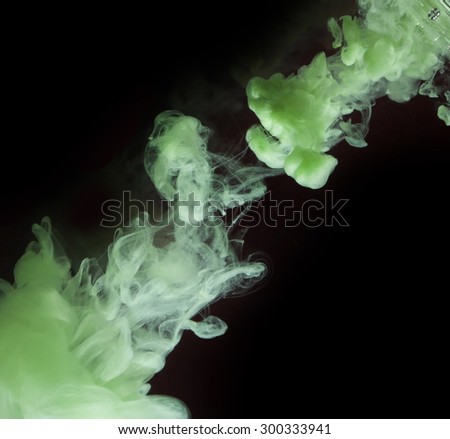 Green paint swirl in water on dark background. Abstraction.