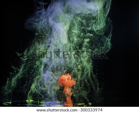 Red and green paint in water on dark background. Abstraction.