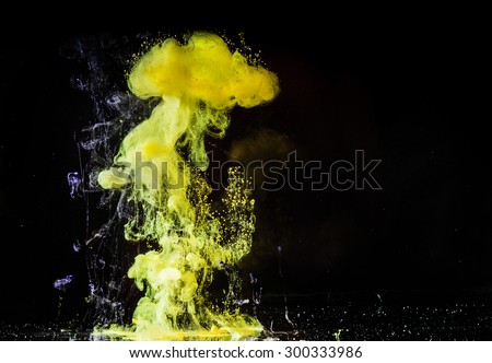 Yellow paint swirl in water on dark background. Abstraction.