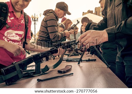 KIEV, UKRAINE - OCTOBER 12, 2014: An Azov battalion soldiers train street passers-by in assembling and disassembling an AK-47 rifle and RPK-74 light machine gun.