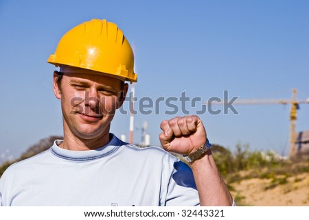 Worker in a hard hat raising his hand as a sign of success.