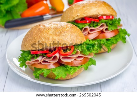 Healthy sandwiches with ham and a wooden board with vegetables on background