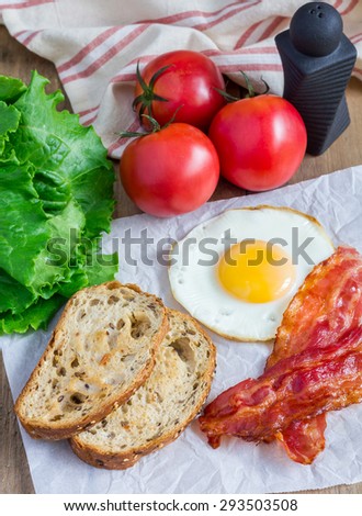 Making open face sandwich with egg, bacon, tomato and lettuce