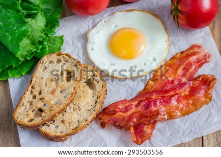 Making open face sandwich with egg, bacon, tomato and lettuce