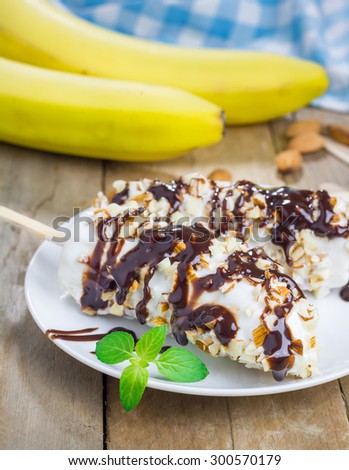 Frozen banana covered with yogurt, almonds and chocolate syrup