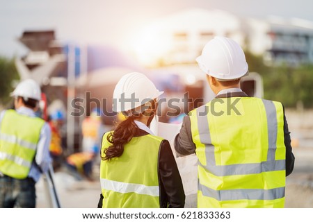 Businessman and businesswoman using see plan paper at construction site