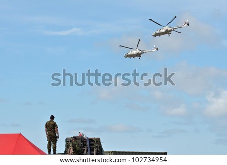 SOUTHPORT, ENGLAND - JULY 23: British Soldiers watch as Two Royal Navy Black Cats Lynx helicopters perform aerobatics and mid air stunts on July 23, 2011 in Southport, England.