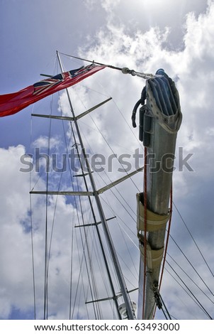 Ships mast with The Merchant Navy Ensign flag flying high on a sunny day.