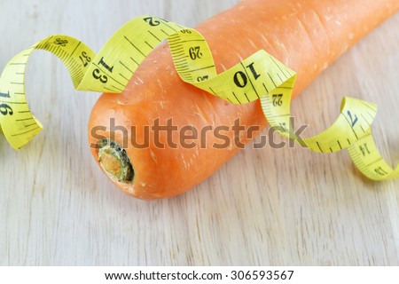 orange carrot and yellow measuring tape on wooden concept for healthy diet and body weight control.