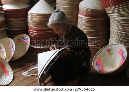 HANOI, VIETNAM - Jun 13, 2015: An elderly woman sat sewing the traditional conical hats at a handicraft villages of Hanoi. This is a woman\'s hat is the most popular Vietnam.