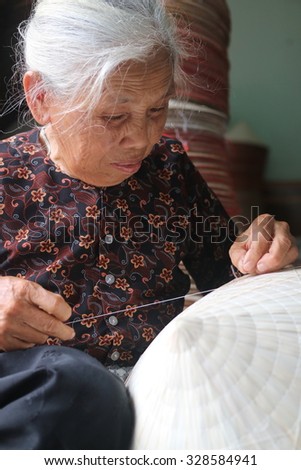 NAMDINH, VIETNAM - June 14, 2015: An elderly woman sat sewing the traditional conical hats at a handicraft villages of Namdinh. This is a woman\'s hat is the most popular Vietnam