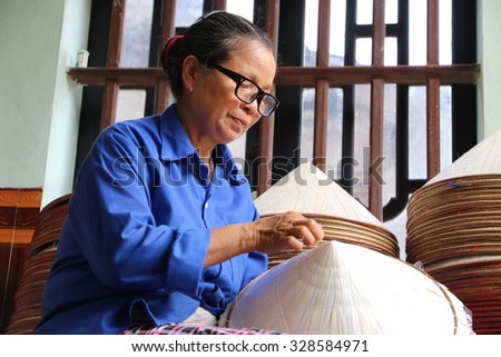 NAMDINH, VIETNAM - June 14, 2015: An elderly woman sat sewing the traditional conical hats at a handicraft villages of Namdinh. This is a woman\'s hat is the most popular Vietnam