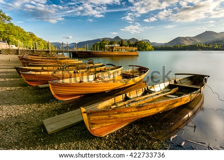 Beautiful evening golden light shining on row of rowing boats at Keswick Boat Launch in the English Lake District.