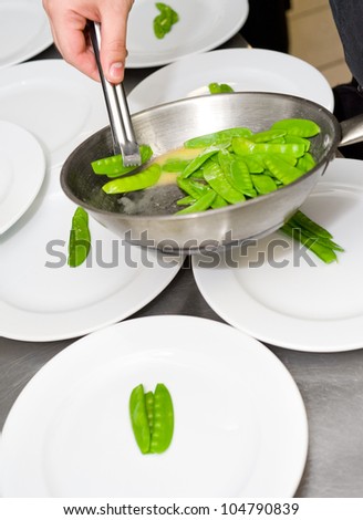 restaurant cooking - a cook lays green pea pods out on plates