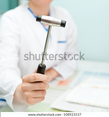 a doctor neuropathologist shows a reflex hammer to camera