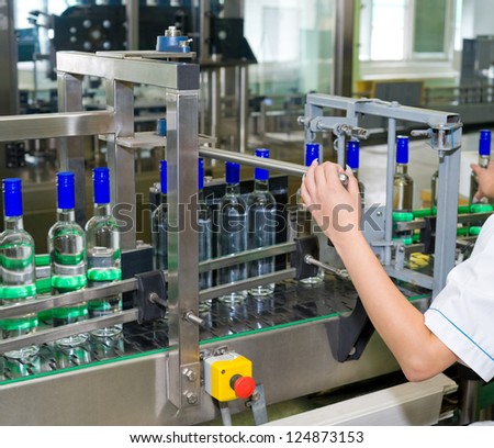 an operator monitors moving vodka bottles on conveyor