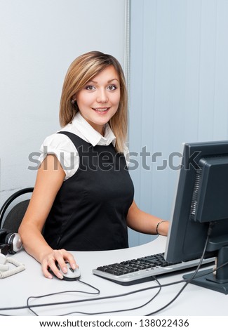 young caucasian woman sitting in front of a computer looks into camera and smiles