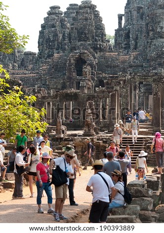 ANGKOR, CAMBODIA - FEB 20, 2013: A lot of tourists watch around Bayon, a temple complex in Angkor Thom. About 20 thousands of tourists visit Angkor Khmer complex every day.