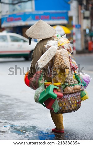 HO CHI MINH, VIETNAM - JULY 8, 2014: An unidentified street vendor carries a lot of various food on a yoke. One can meet many such vendors in the tourist area of the city.