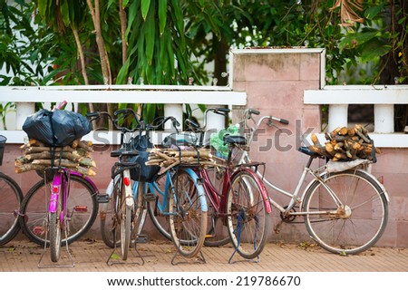 several bicycles with fire wood on luggage racks, Cambodia