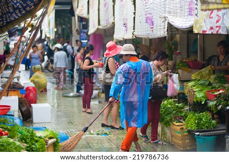 HO CHI MINH, VIETNAM - JULY 5, 2014:  An unidentified man cleaner sweeps the floor at the Ben Thanh Market. While tourists search here souvenirs townspeople come to buy fresh food.
