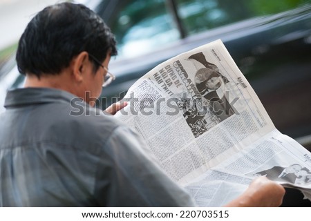 HO CHI MINH, VIETNAM - JULY 8, 2014: An unidentified man reads about Ukraine in a newspaper. Combat operations in the country have not finished until today.