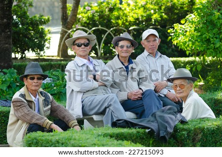 DALAT, VIETNAM - JUNE 8, 2014: A group of unidentified Vietnamese senior men having a rest in a park pose for camera. The park near the city market is favoured by townspeople.