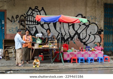PHNOM PENH, CAMBODIA - JULY 3, 2014: An unidentified Asian woman takes money from a man at a street cafe in the downtown.