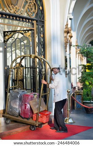 HO CHI MINH, VIETNAM - JAN 15, 2015: An unidentified porter pulls a cart with suitcases into the entrance door of the hotel Majestic. It is a luxury hotel built in 1925 on the Saigon River bank.
