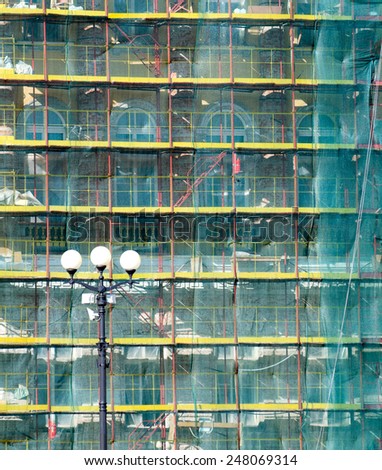 architectural restoration - an old building in green mesh and scaffolding