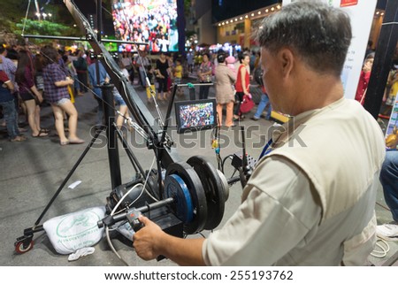 HO CHI MINH, VIETNAM - FEB 22, 2015: An unidentified cameraman shoots people walking in the downton on Tet. They can see themselves on a large screen at once.