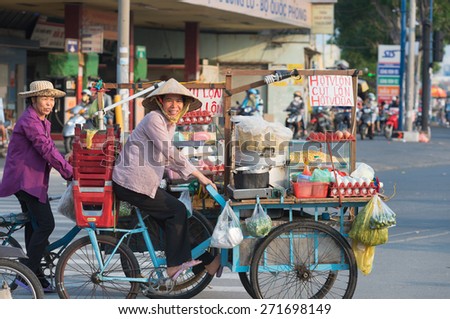 HO CHI MINH - APRIL 19, 2015: Two unidentified local women cooks drive their bicycle carts along Truong Chinh Street to their point of work. Their business is cooking food in the street.