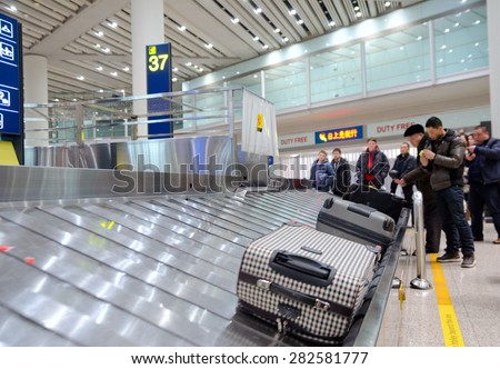 BEIJING - FEBRUARY 16: Unidentified air passengers wait for their baggage at Beijing airport luggage claim area, February 16, 2013 Beijing, China.