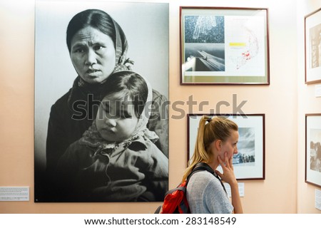 HO CHI MINH, VIETNAM - JULY 15, 2014: A Caucasian woman watches photographs at the War Remnants Museum. It primarily contains exhibits relating to the American phase of the Vietnam War.
