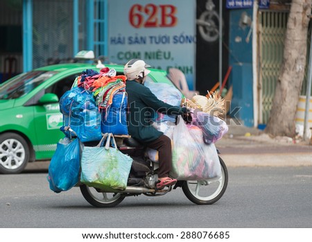 VUNG TAU, VIETNAM - JUNE 10, 2015: An unidentified woman carries lots of bags and sacks by her motorbike. The main means of cargo transportation in Vietnam is motorcycle.