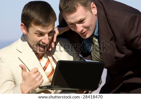 two excited European businessmen laugh watching laptop