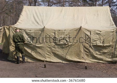 soldier arranging window of large military tent