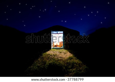 there is light from the open door of yurta house standing against night dark blue sky with stars
